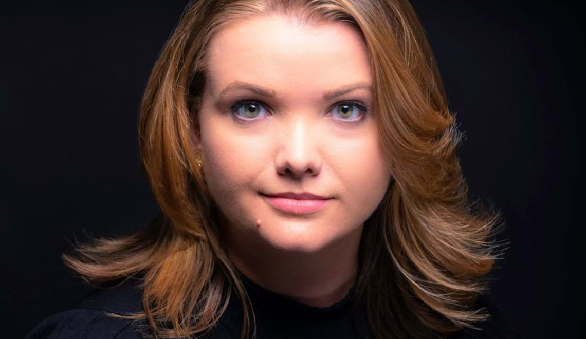 Téa Obreht has brown hair and wears a black top in front of a black background.